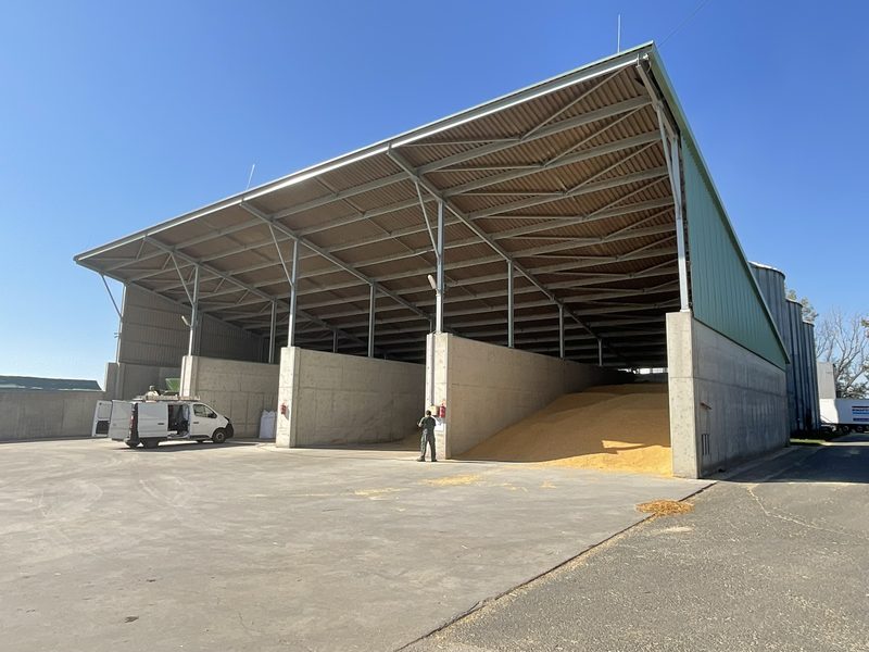 Reinforced concrete retaining bays under a long-span steel roof.