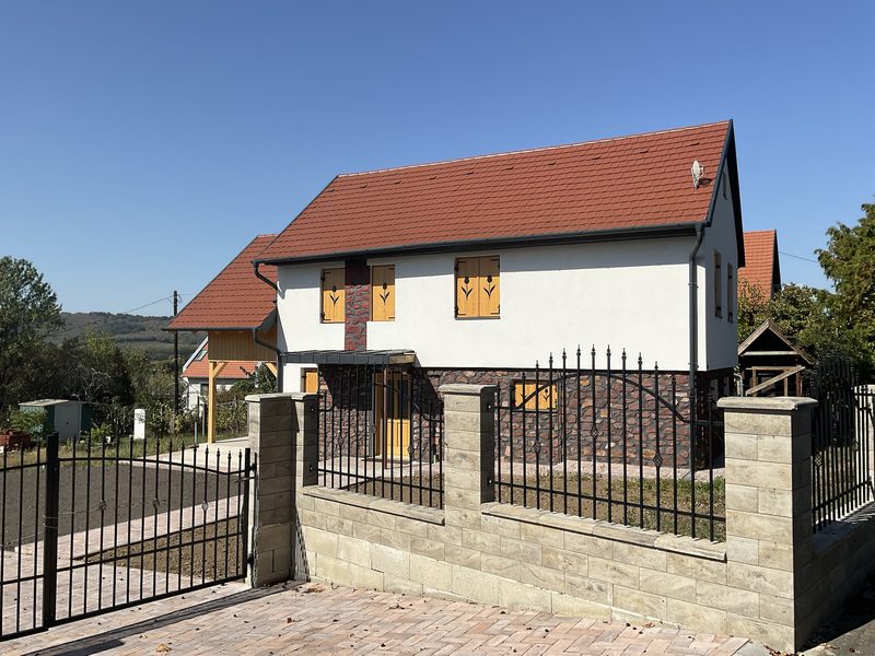 A glazed canopy over the entrance, with the hillside and neighbouring press houses behind.