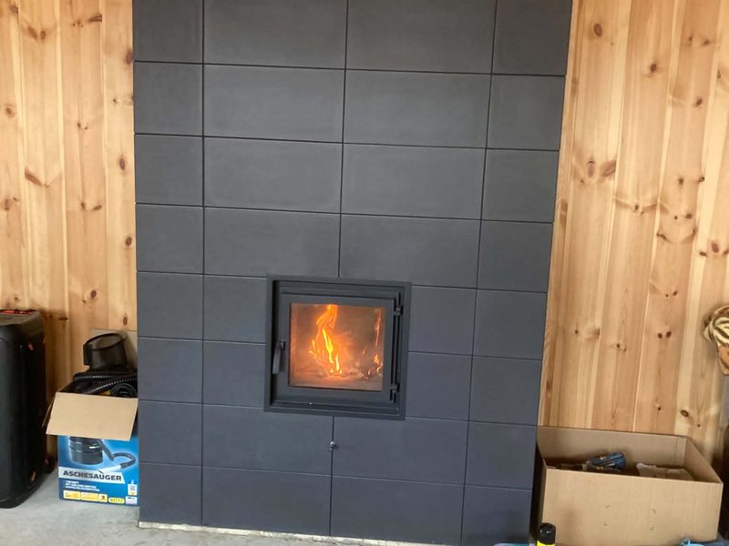 Der verkleidete Kamin an der holzverkleideten Wand.