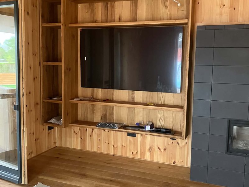 Eingebaute Holzregalwand im Wohnzimmer neben dem Kamin.