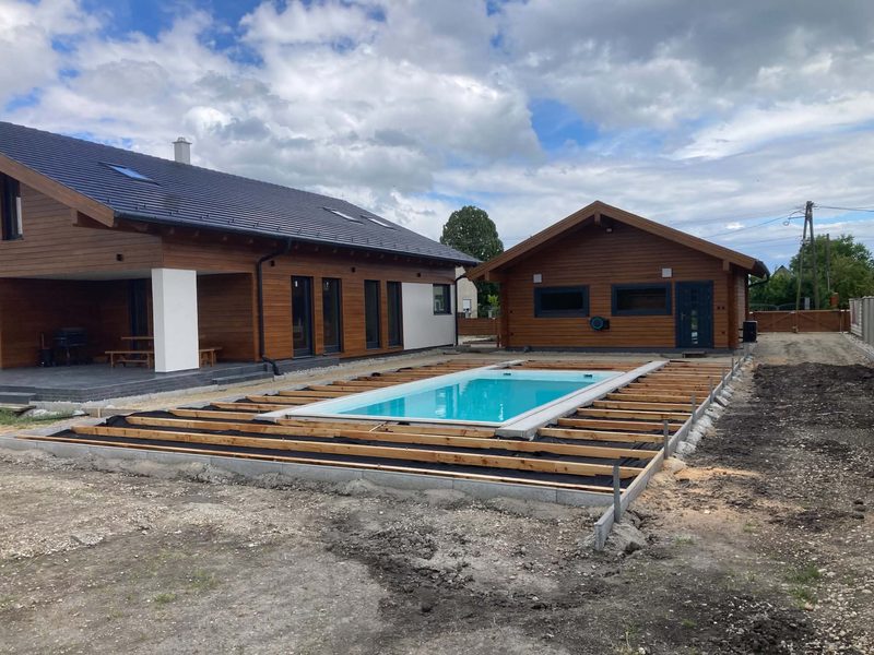 Der Pool mit der Unterkonstruktion der Terrasse, dahinter Haus und Nebengebäude.